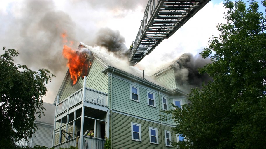 2-story house on fire with fire ladder extended to it